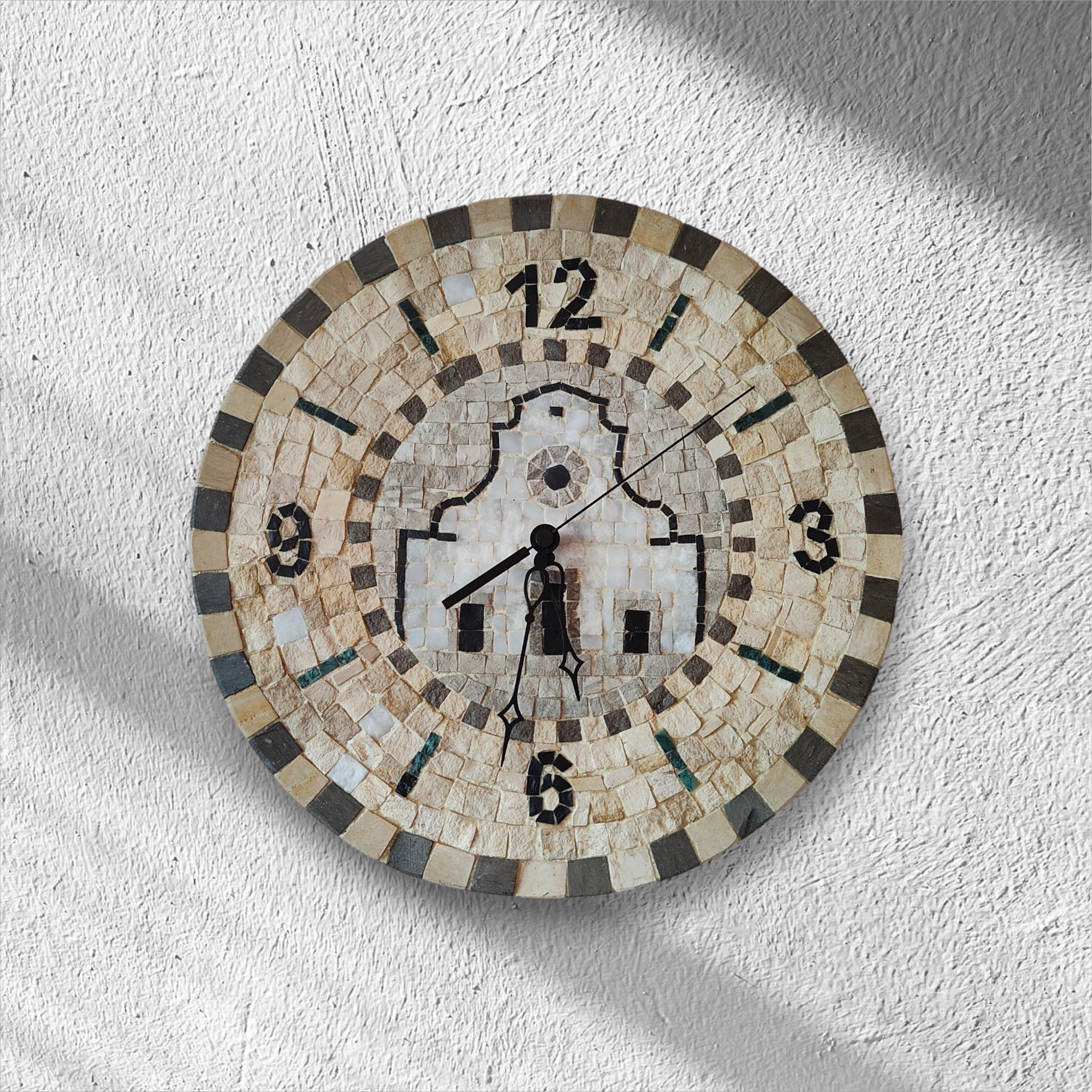 Un orologio a mosaico su una parete bianca segna le 10:10