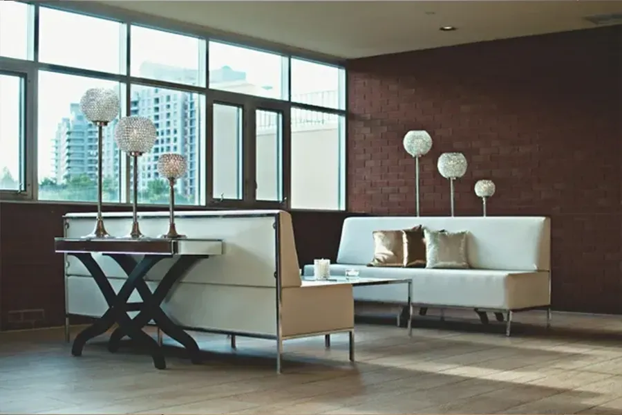 Modern lounge with white sofas, glass table, and globe floor lamps by large windows
