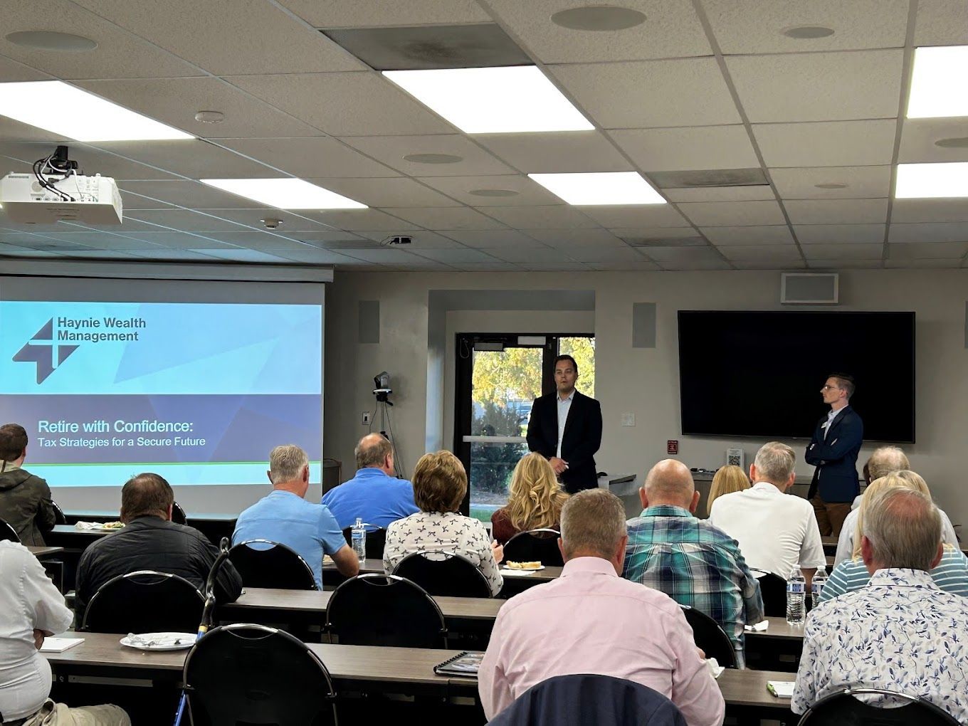 A man is giving a presentation to a group of people in a classroom.