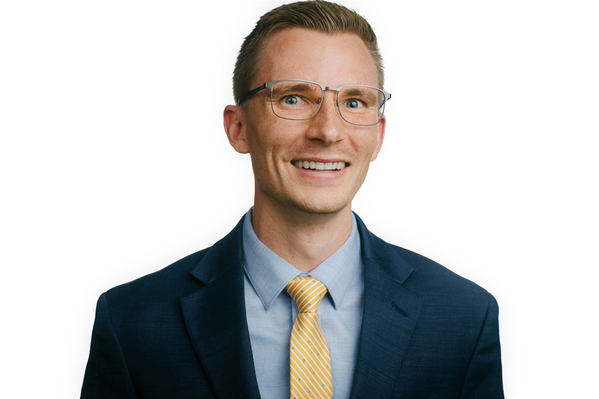 A man in a suit and tie is smiling and wearing glasses.