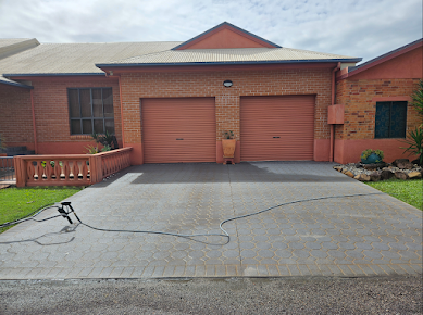 A Brick House With a Concrete Driveway in Front of It — DJ's Pressure Cleaning In Carruchan, QLD