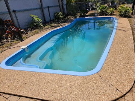 A Large Swimming Pool is Sitting on Top of a Concrete Patio — DJ's Pressure Cleaning In Tully, QLD