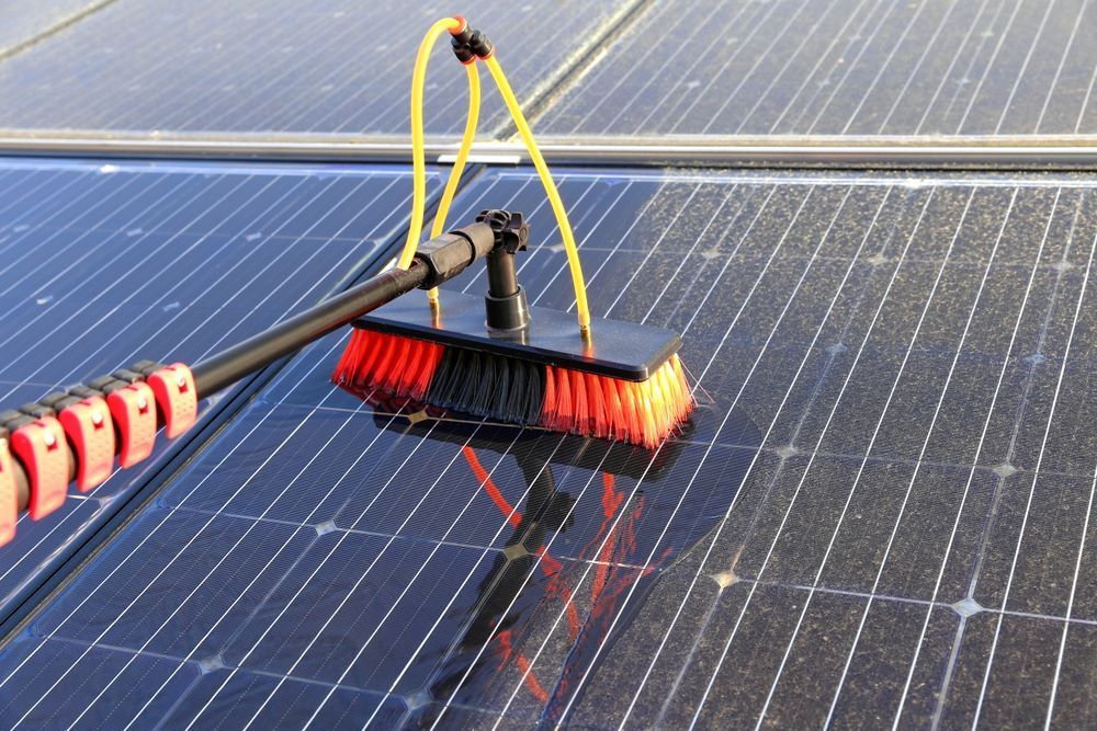 A Person is Cleaning a Solar Panel With a Brush — DJ's Pressure Cleaning In Mission Beach, QLD
