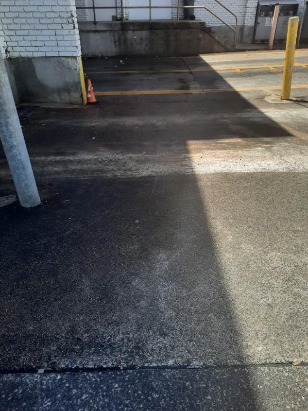 A Parking Lot With a White Brick Building in the Background — DJ's Pressure Cleaning In Carruchan, QLD