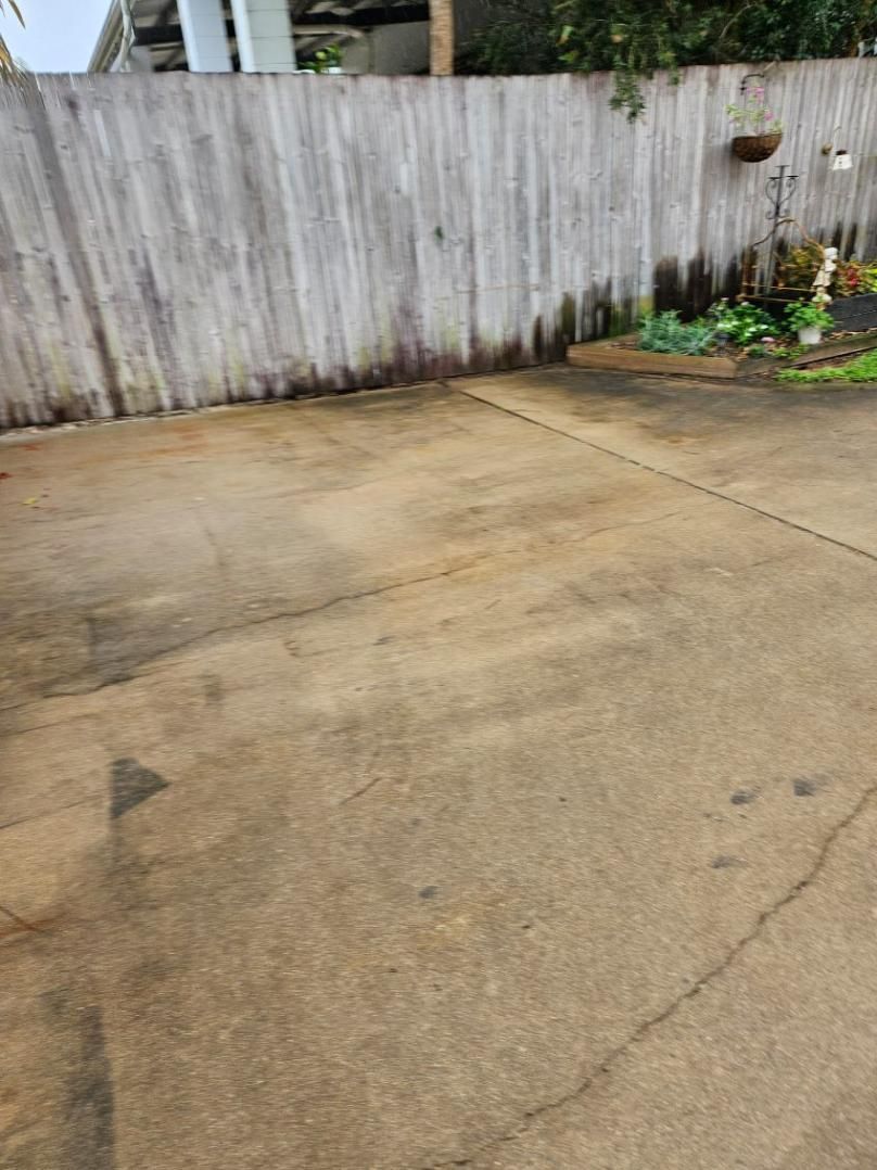 A Concrete Driveway With a Wooden Fence in the Background — DJ's Pressure Cleaning In Carruchan, QLD