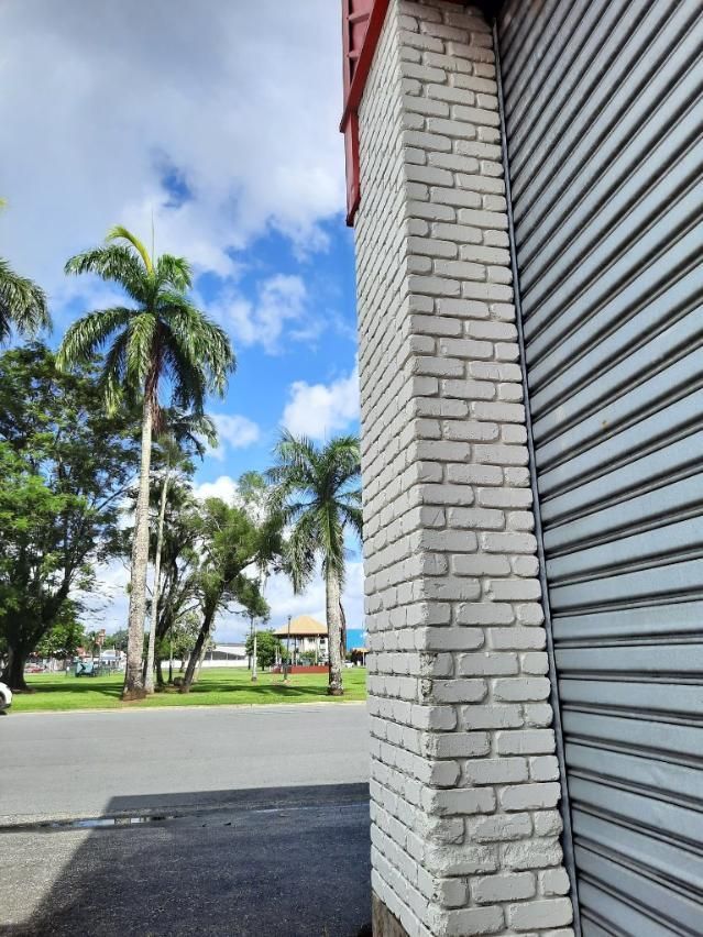 A Brick Building With a Metal Garage Door and a Palm Tree in the Background — DJ's Pressure Cleaning In Mission Beach, QLD