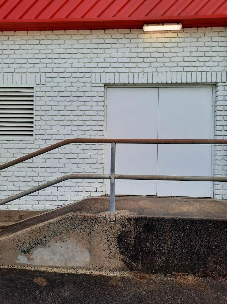 A White Brick Building With a Red Roof and Stairs Leading Up to It — DJ's Pressure Cleaning In Carruchan, QLD