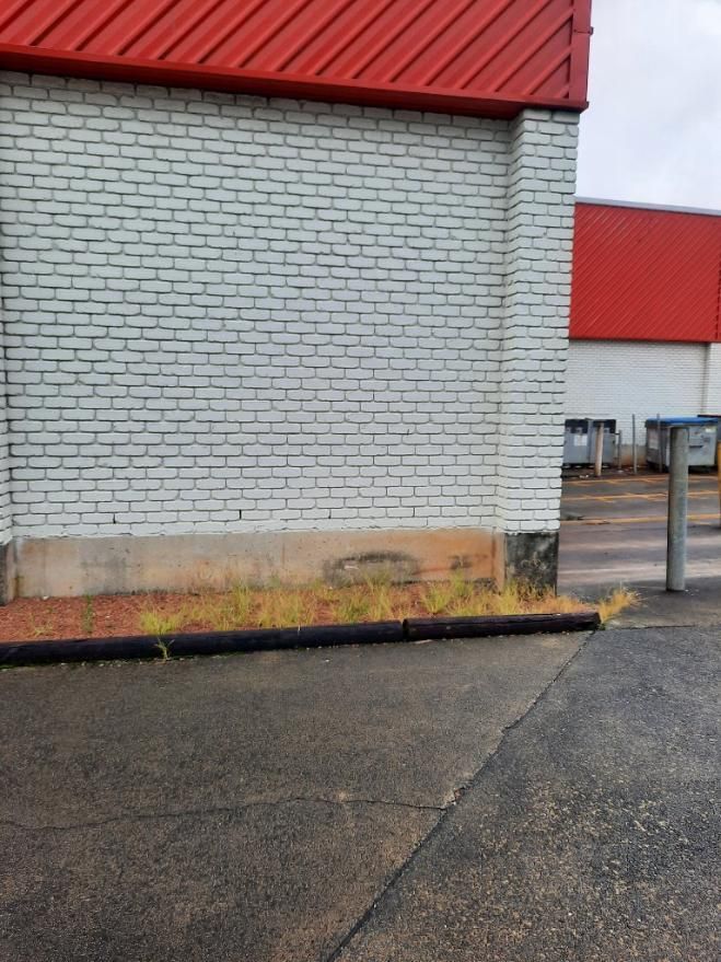 A White Brick Building With a Red Roof is Next to a Parking Lot — DJ's Pressure Cleaning In Carruchan, QLD