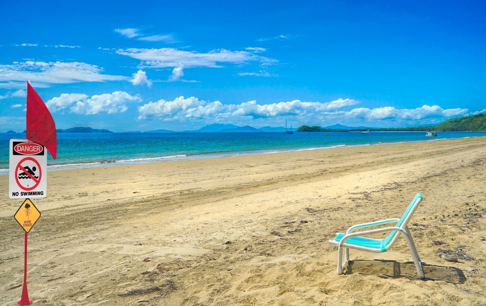 A Chair is Sitting on the Beach Next to a Sign That Says No Diving — DJ's Pressure Cleaning In Mission Beach, QLD