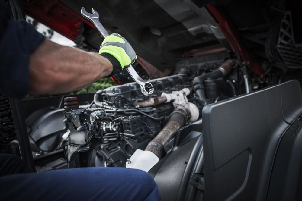 A Man Is Working On A Truck Engine With A Wrench — Newcastle Truck Repairs in Thornton, NSW