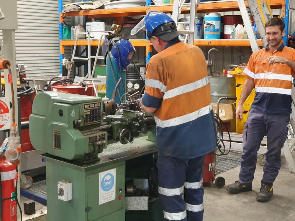 A Group Of Men Are Working On A Machine In A Factory — Newcastle Truck Repairs in Thornton, NSW