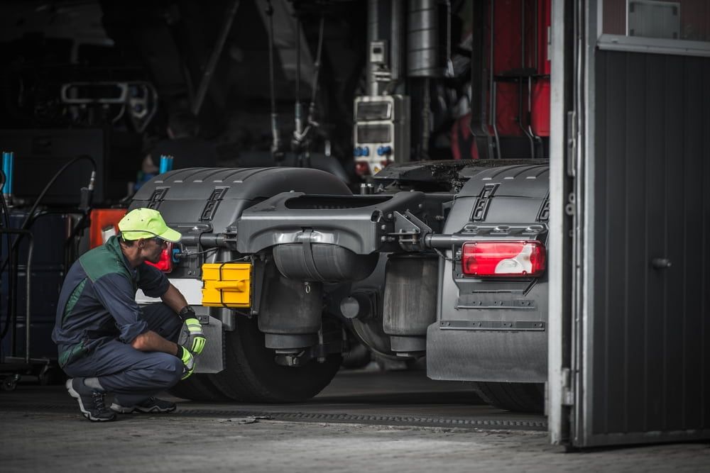 A Man Is Working On A Semi Truck In A Garage  — Newcastle Truck Repairs in Maitland, NSW