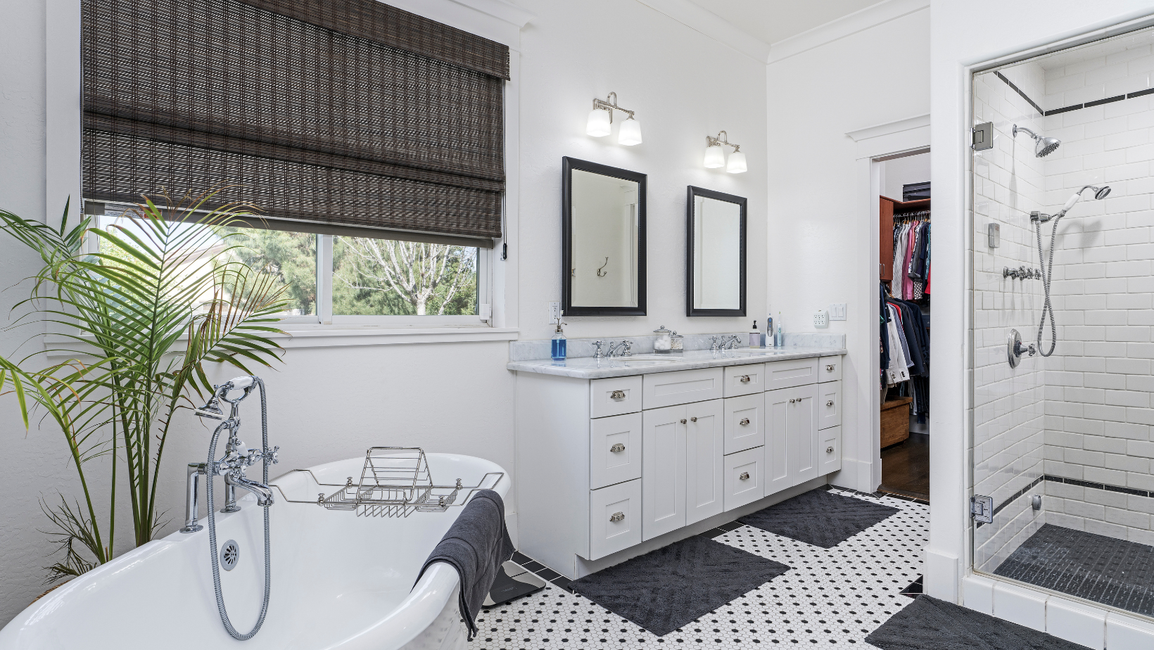 Bright white bathroom with black and white tile, a bathtub, and a glass-enclosed shower.
