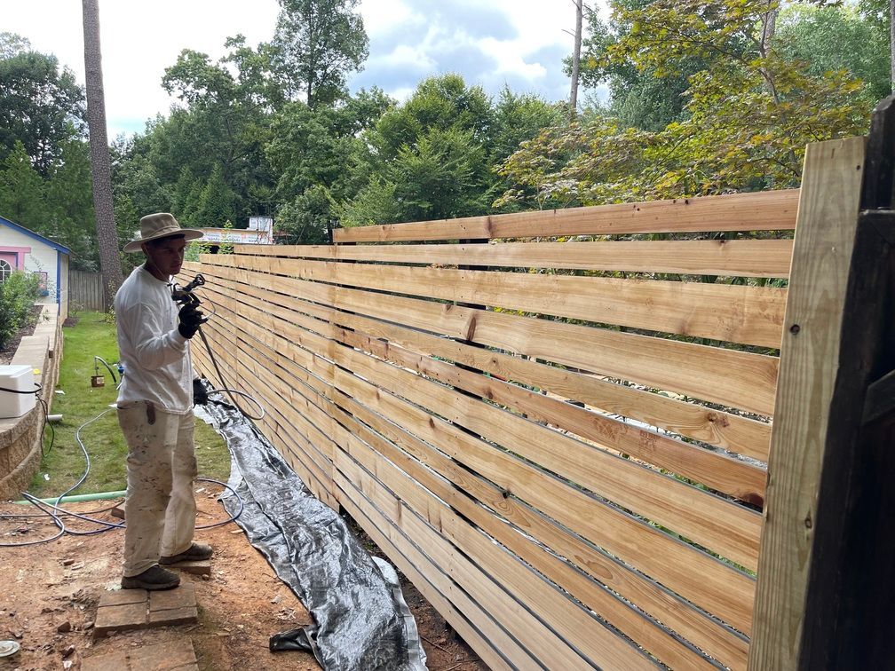 A man is standing next to a wooden fence.