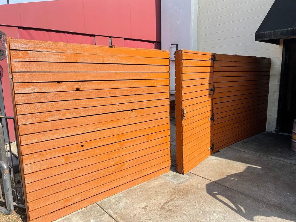 A wooden fence is sitting on a sidewalk in front of a building.