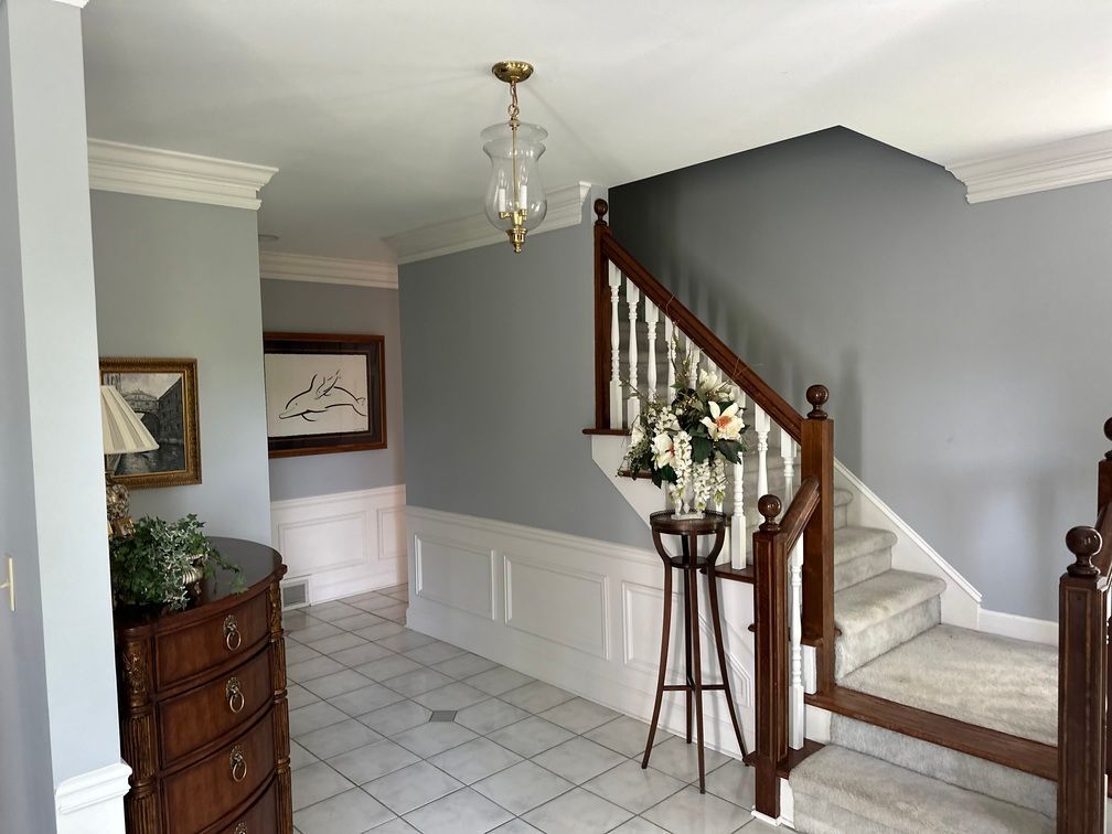 A hallway with a staircase and a dresser