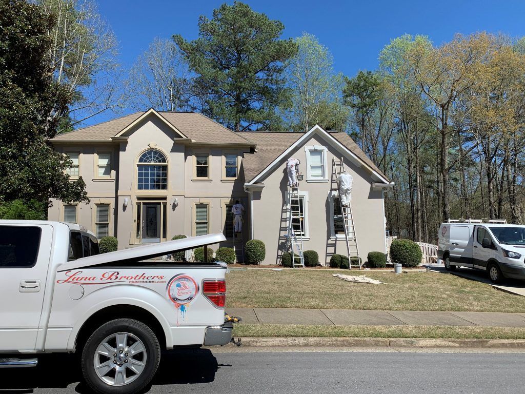 A white truck is parked in front of a large house.