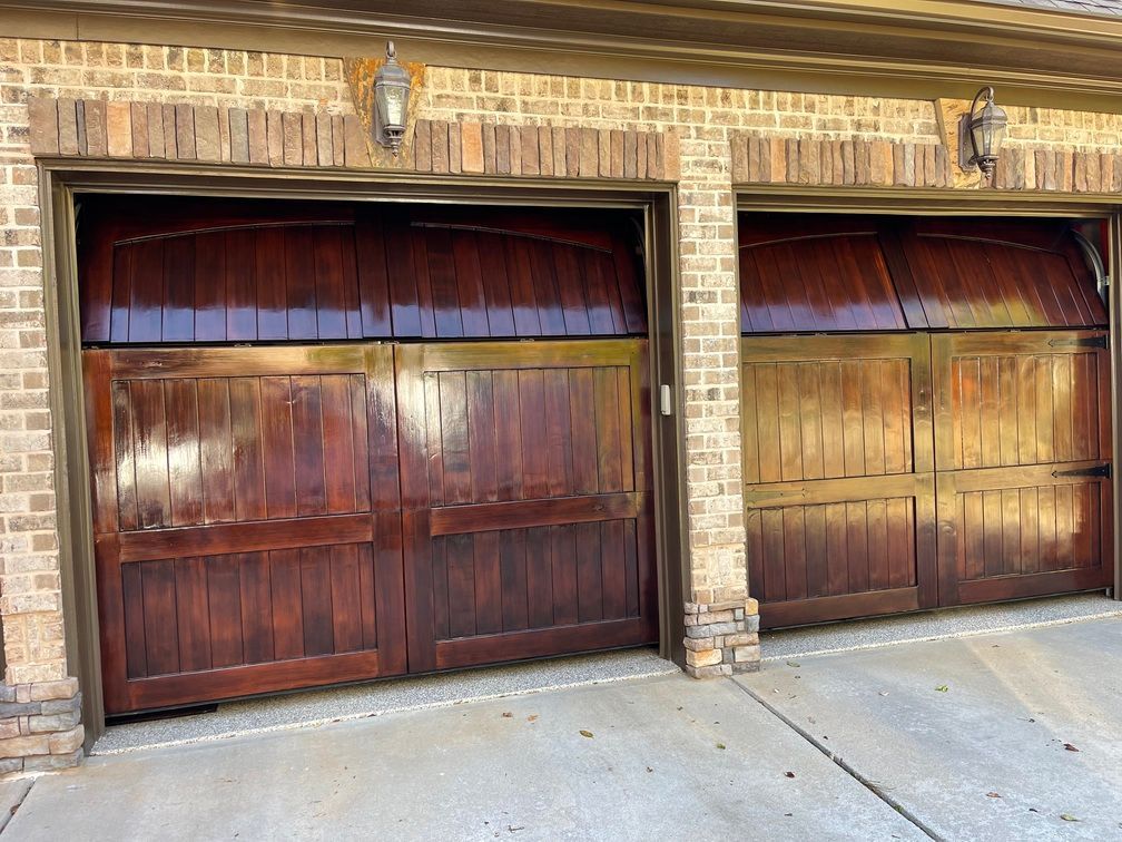 A pair of wooden garage doors on a brick building.