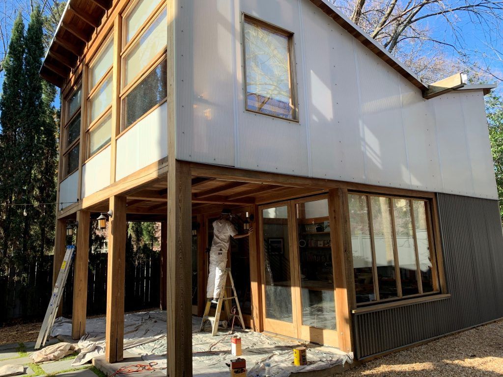 A man is standing on a ladder in front of a house.