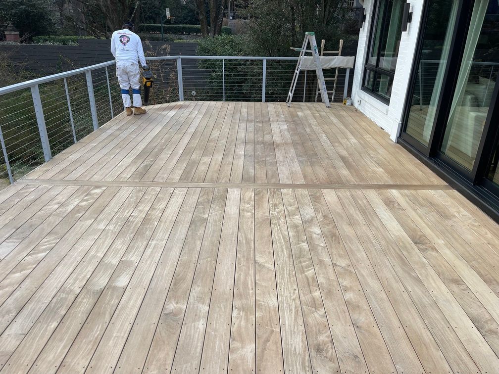 A man is standing on a wooden deck with a ladder.