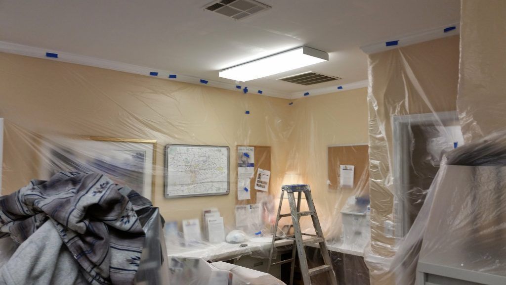 A room is being painted with plastic covering the walls and ceiling.