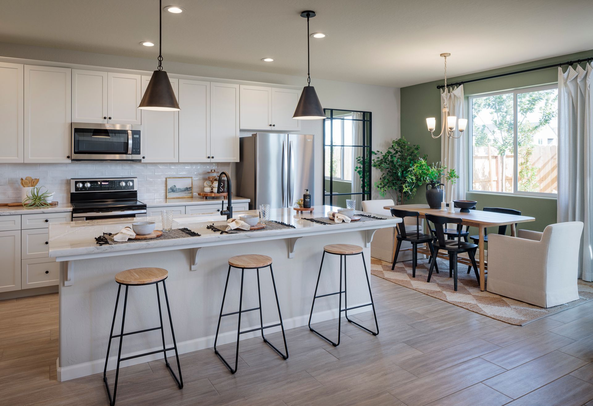 Modern open-concept kitchen with white cabinets, large island seating, stainless steel appliances
