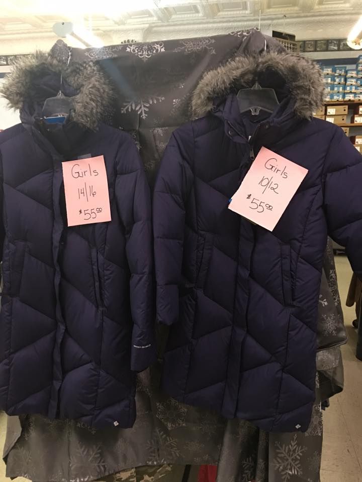 A couple of jackets are hanging on a rack in a store