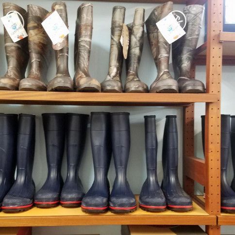 A row of rubber boots are lined up on a shelf