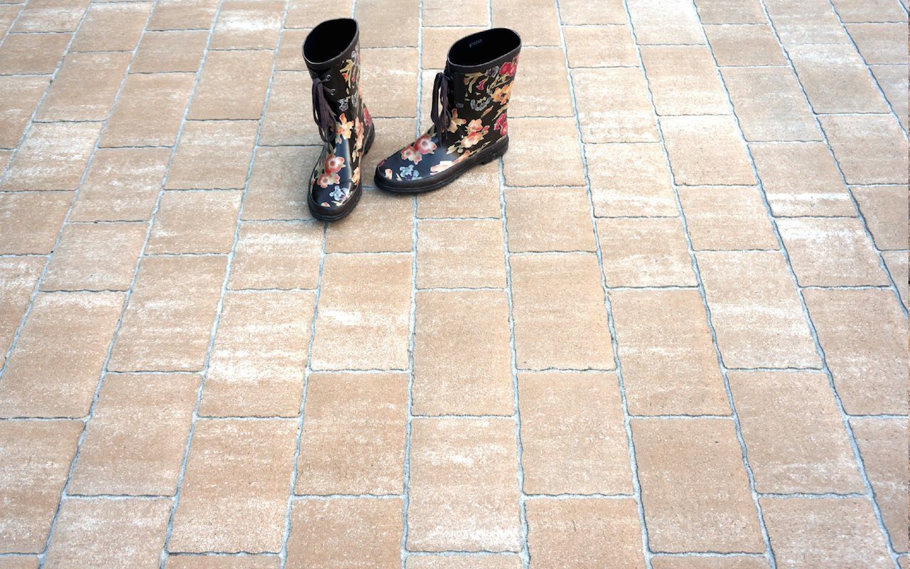 Ein Paar Gummistiefel stehen auf einem Ziegelboden.