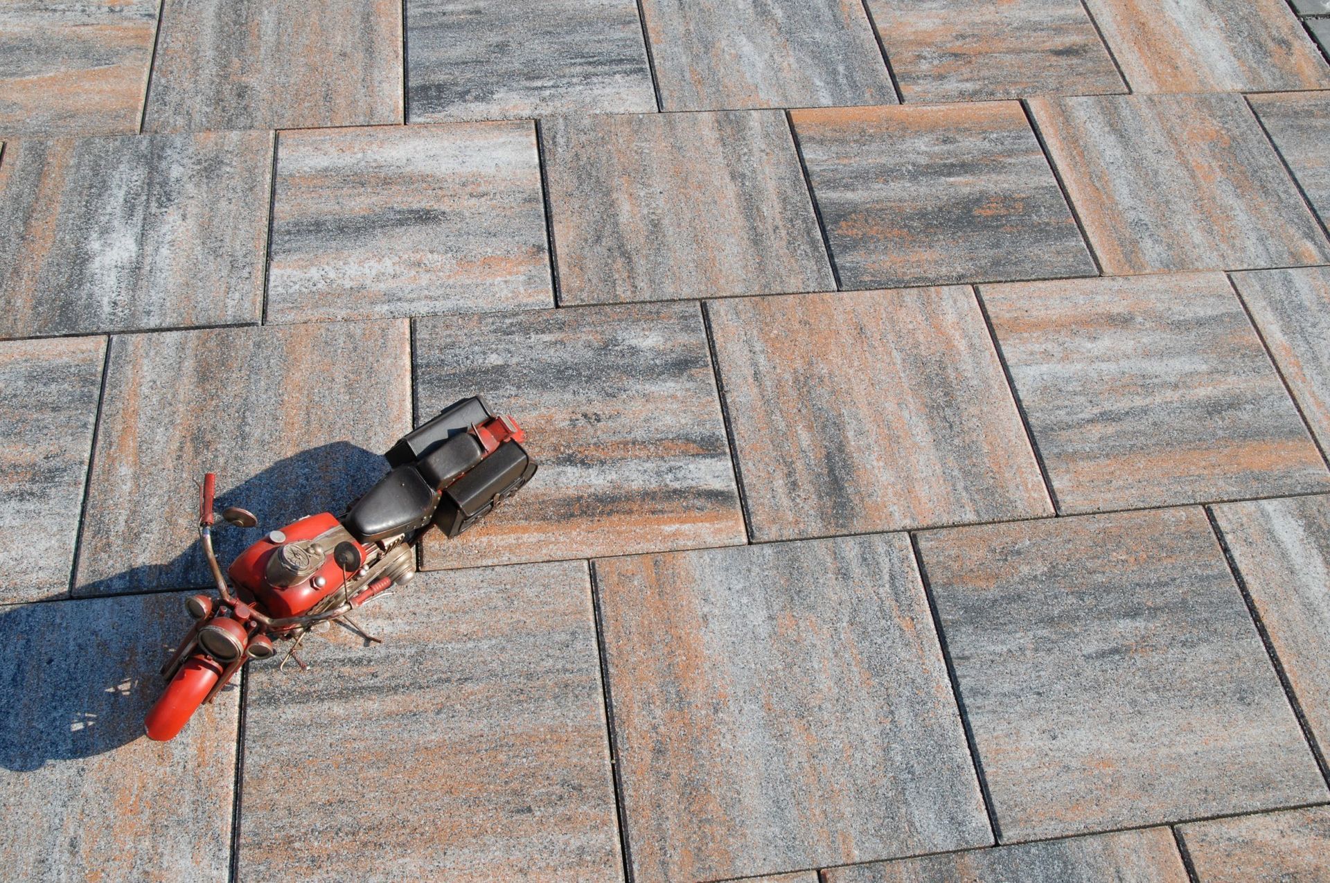 Auf einem Ziegelsteinpflaster liegt ein Spielzeugmotorrad.
