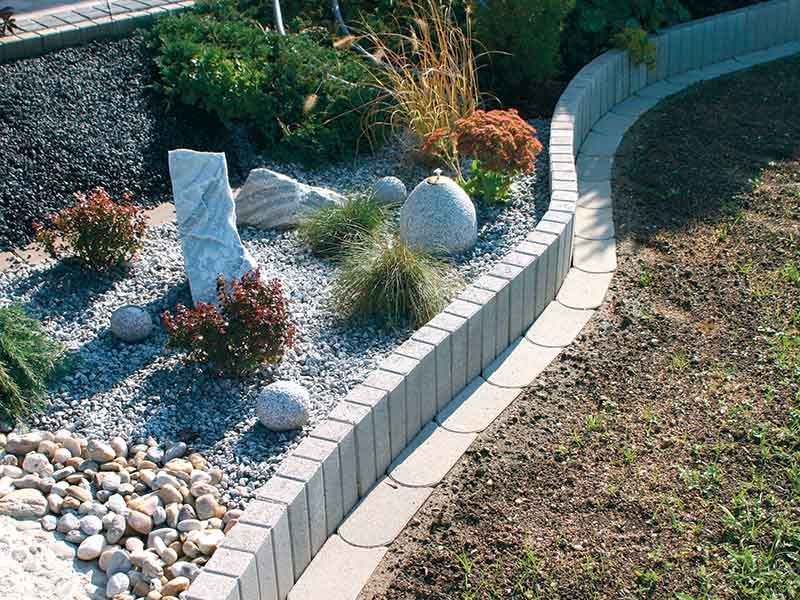 Ein Garten mit Felsen und Pflanzen und einer Ziegelumrandung