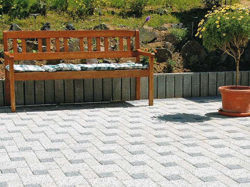 Eine Holzbank steht auf einer Terrasse neben einer Topfpflanze