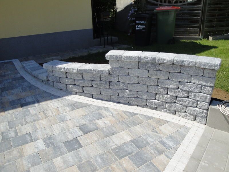 Neben einem gemauerten Gehweg steht eine Backsteinmauer.