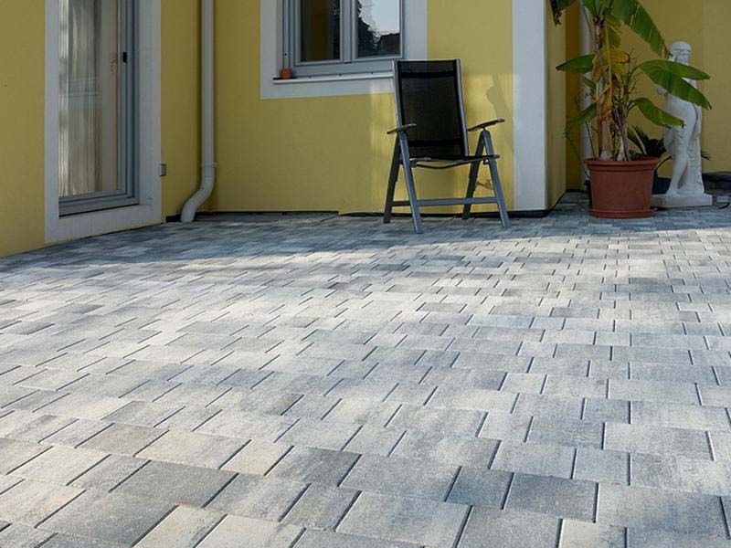 Ein schwarzer Stuhl steht auf einer Terrasse vor einem gelben Haus