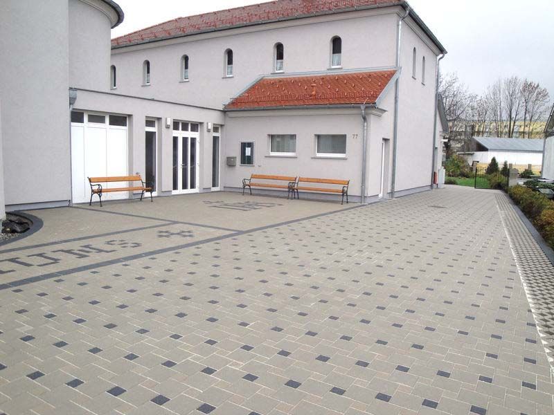 Ein weißes Gebäude mit einem roten Dach und einer gemauerten Auffahrt