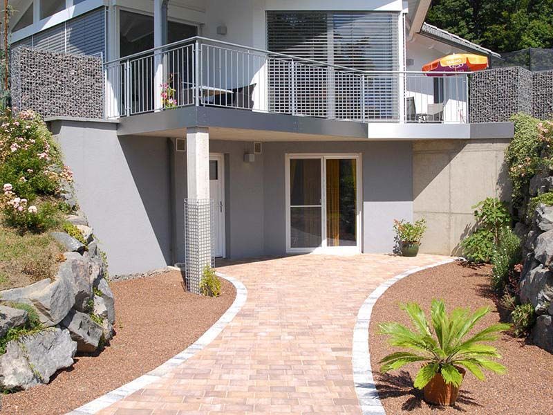 Ein Haus mit einem Balkon und einem dorthin führenden Gehweg