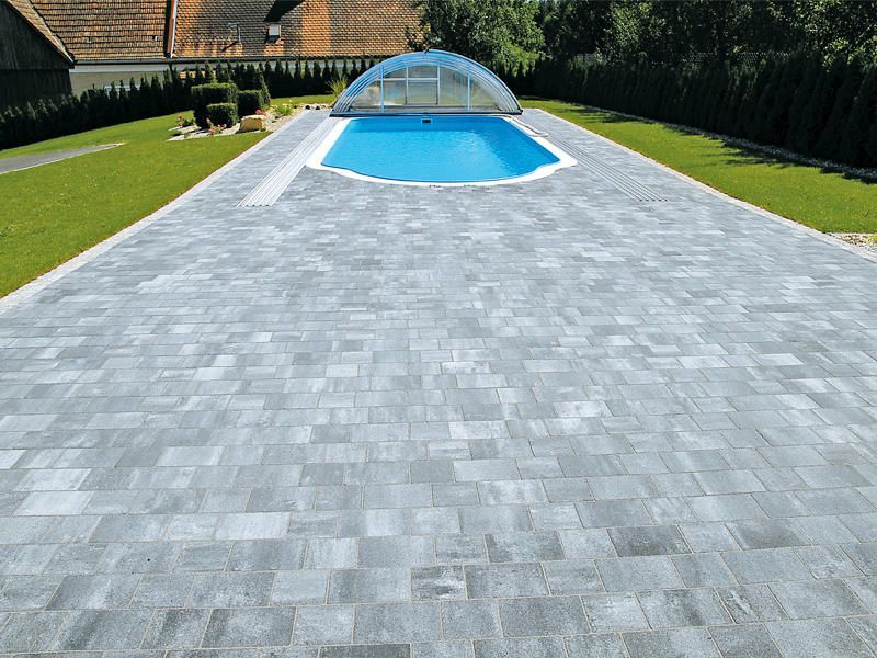 Ein großer Swimmingpool ist von einem gemauerten Gehweg umgeben