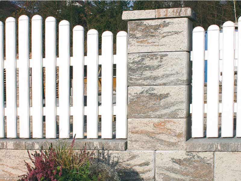 Ein weißer Lattenzaun umgibt eine Steinmauer