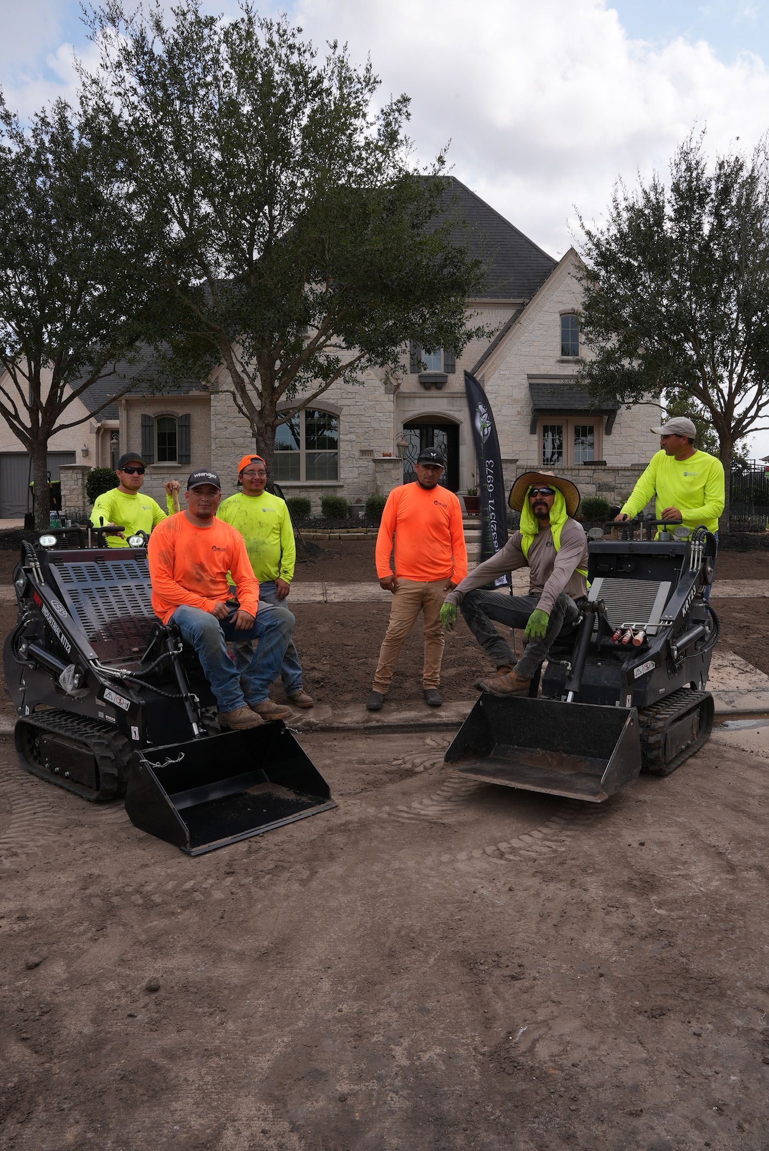 A group of construction workers are posing for a picture in front of a house.