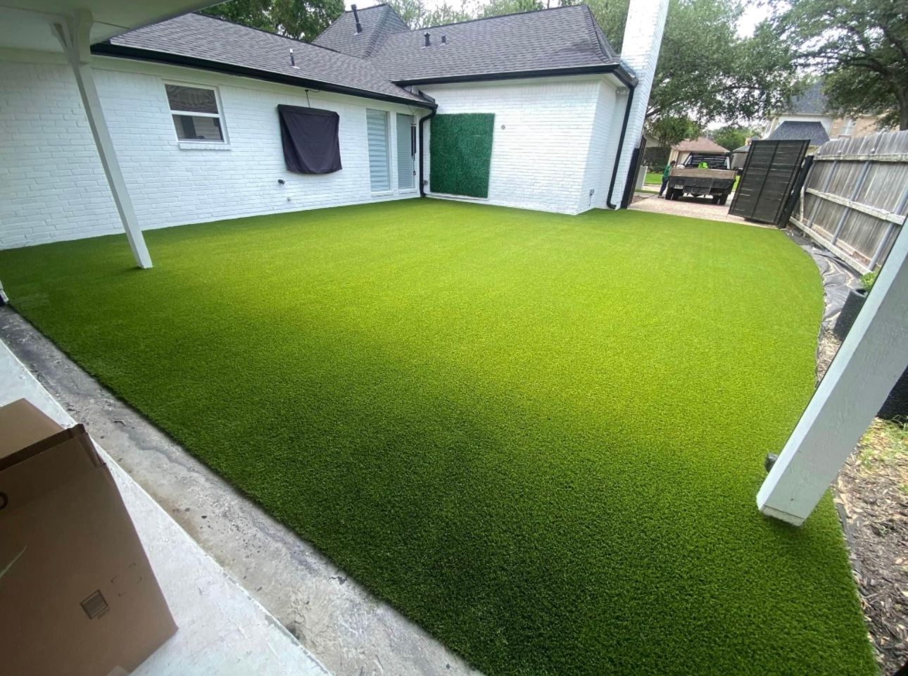 A backyard with a lot of green grass and a white house in the background.