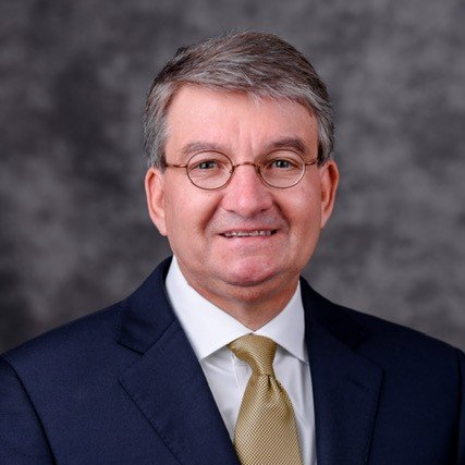 A man in a suit and tie is smiling for the camera