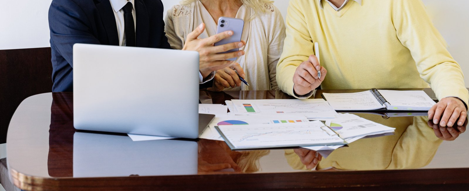 A group of people are sitting at a table with a laptop and papers.