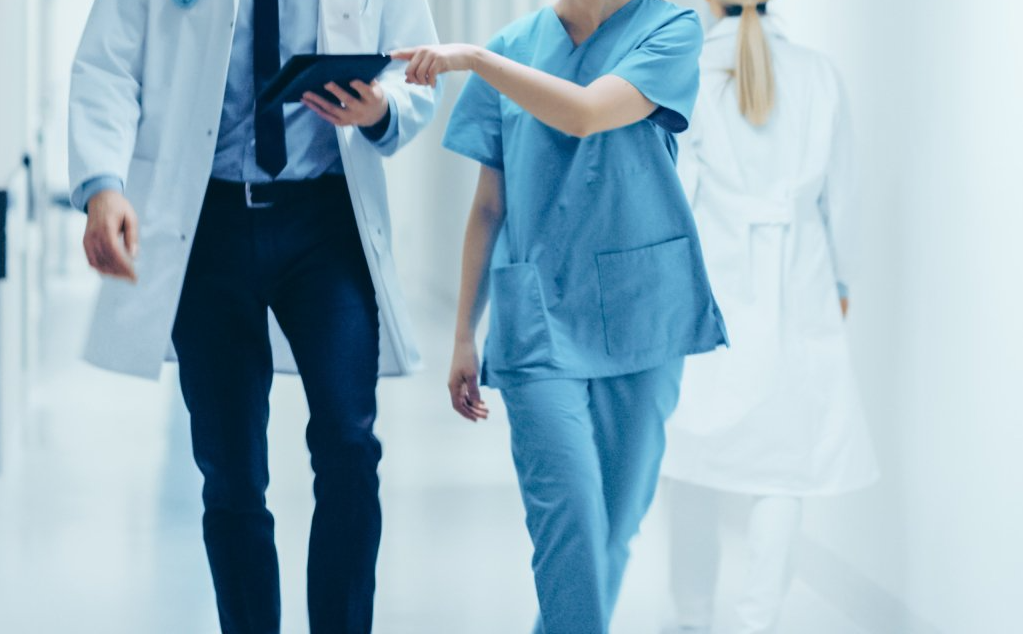 A doctor and a nurse are walking down a hospital hallway.