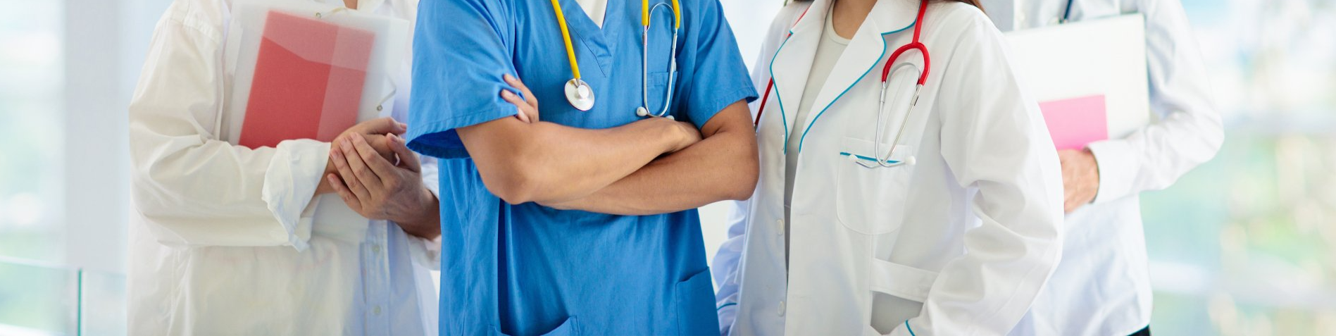 A group of doctors and nurses are standing next to each other with their arms crossed.