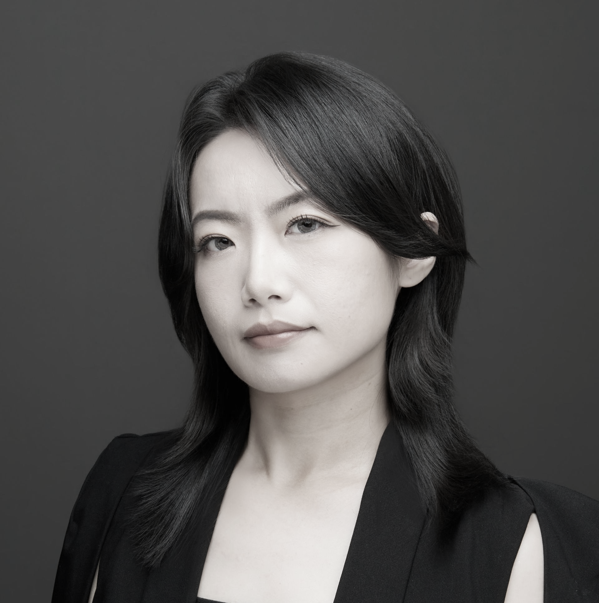 一張黑白照片中,一位穿著西裝和白襯衫的女人微笑著。