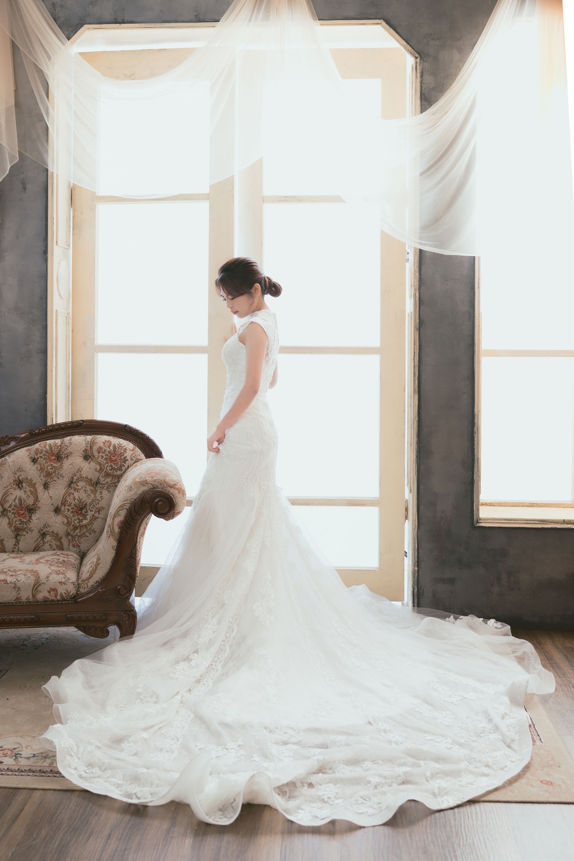 一個穿著婚紗的女人站在房間裡的沙發旁。