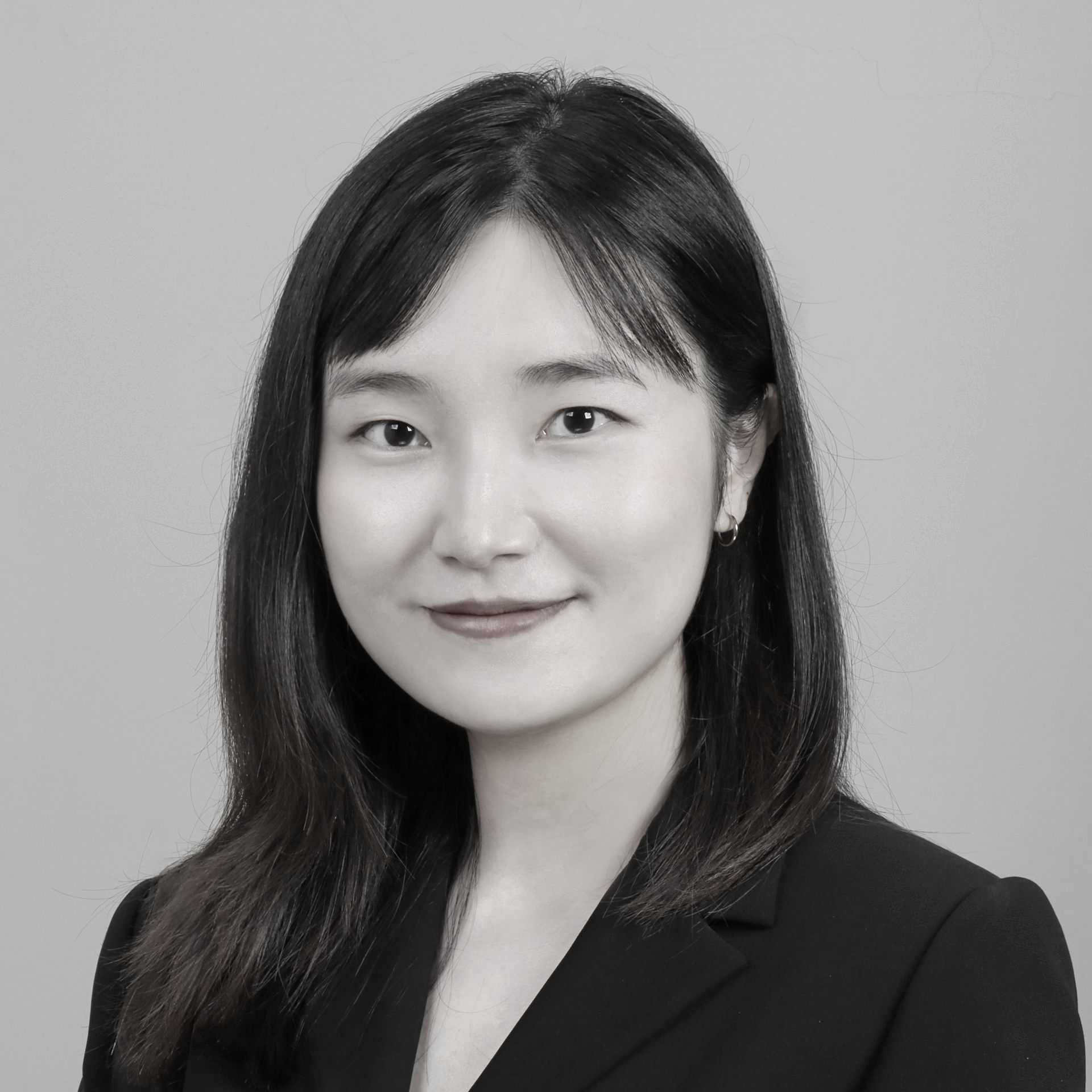 黑白照片中,一名身穿白色夾克的女子微笑著。