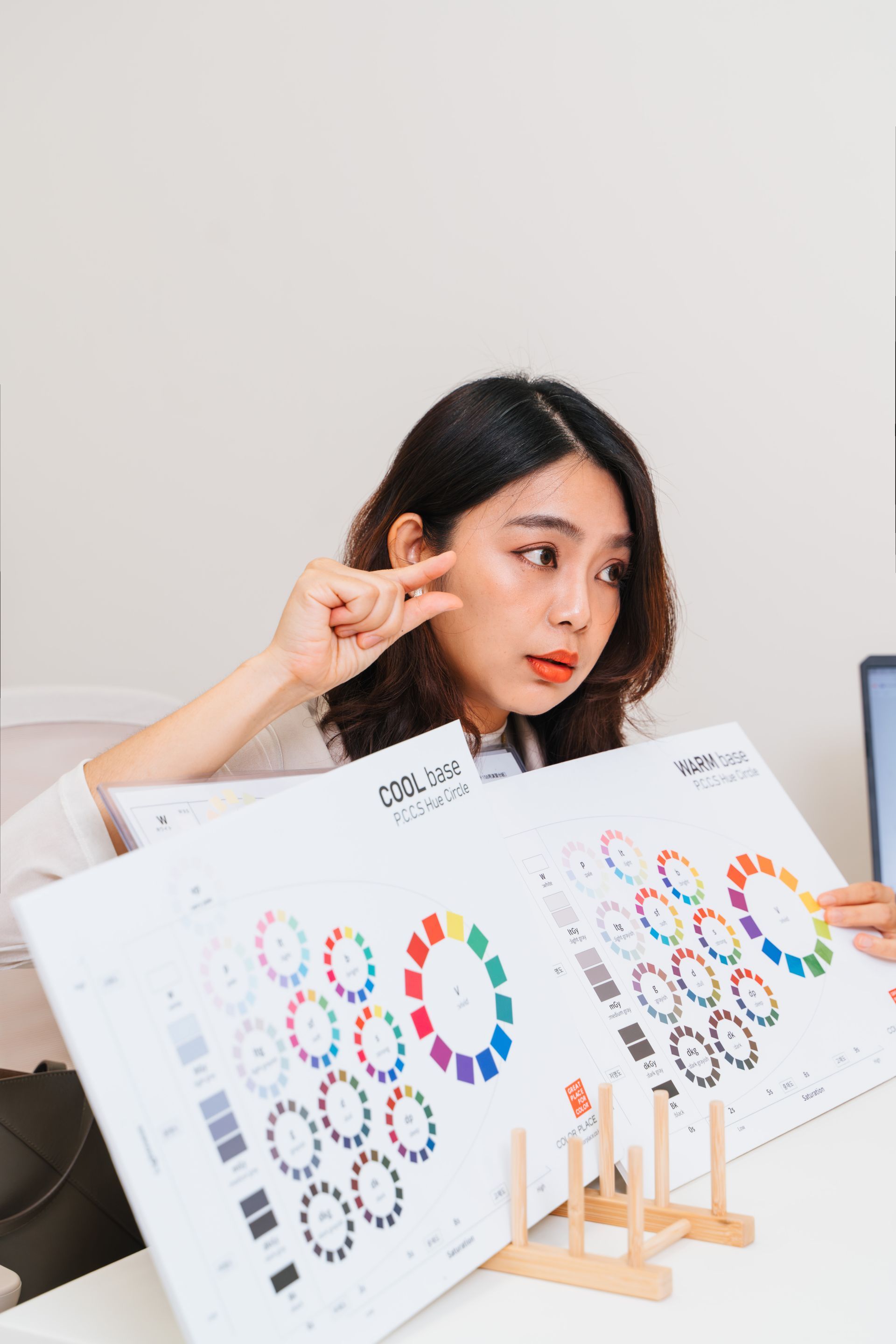 一位女士坐在辦公桌前，手裡拿著一個調色盤。