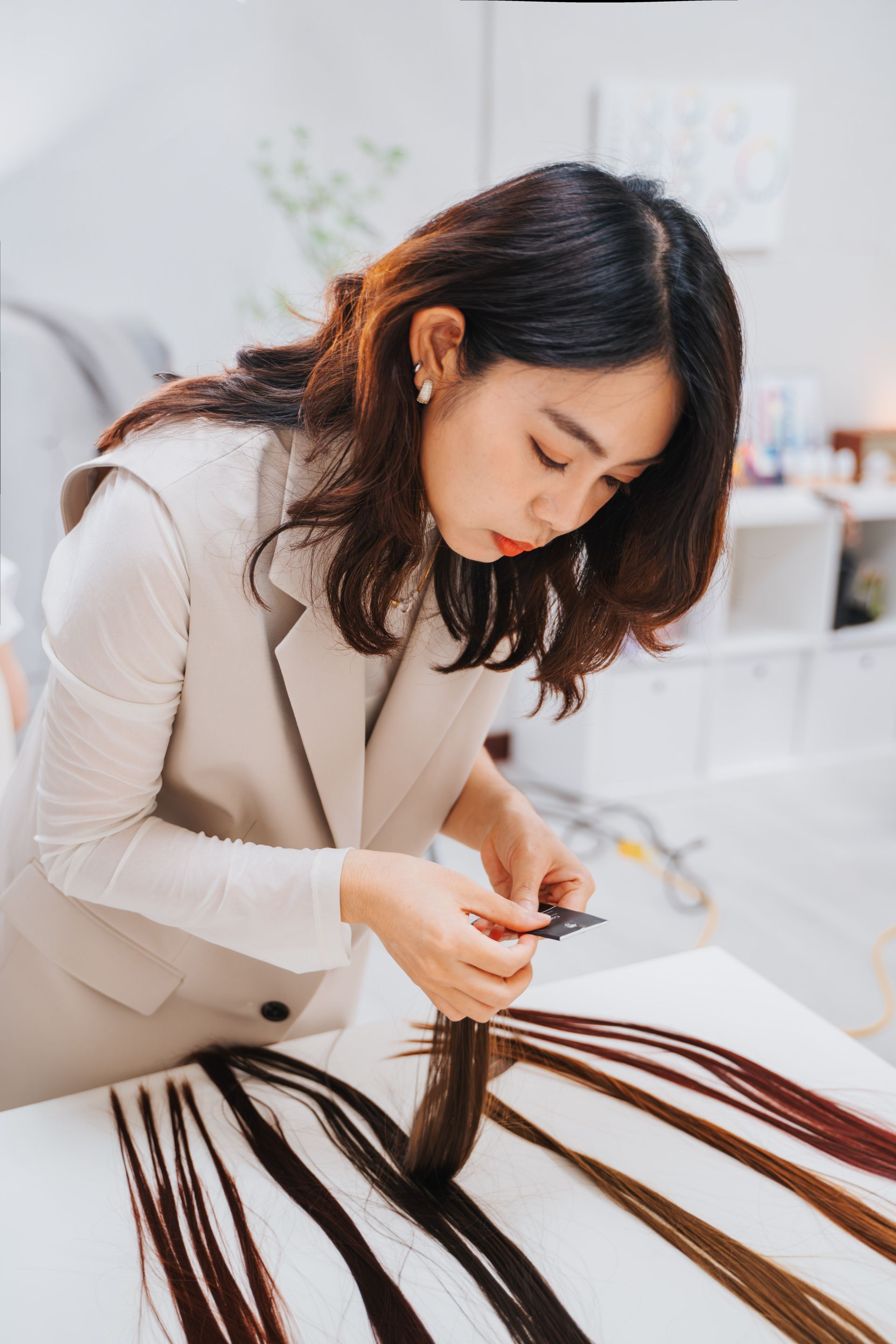 一個女人坐在一張桌子旁，手裡拿著一束接髮。