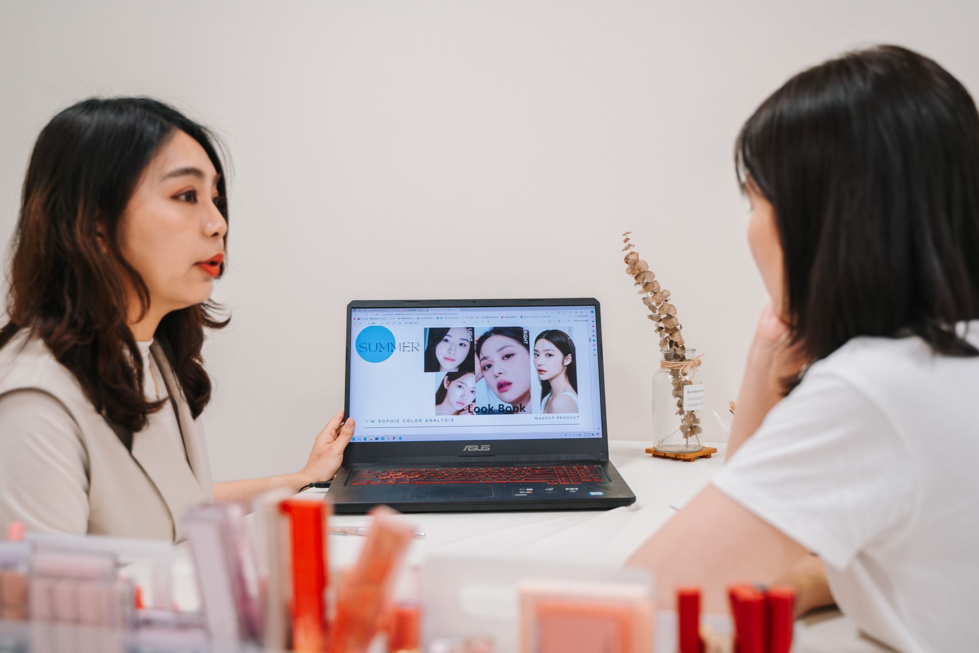 兩個女人坐在桌子旁看著一台筆記型電腦。